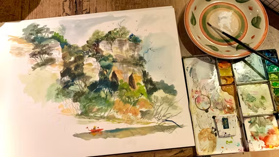 Aquarelle d'un paysage avec des falaises verdoyantes et un petit canoë sur l'eau, accompagnée d'une palette de peinture et d'un plat pour mélanger les couleurs.
